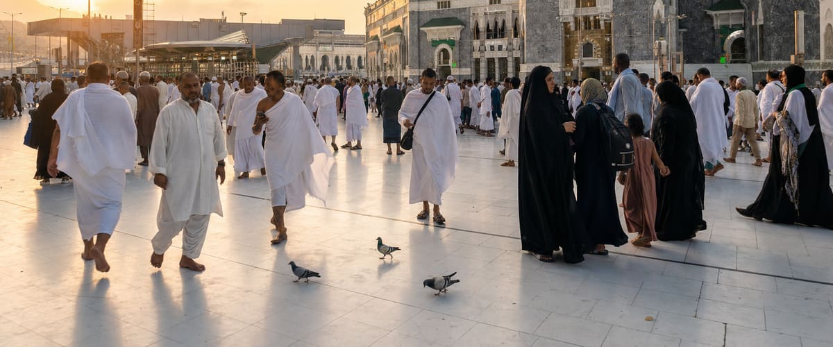 Pilgrims crossing the white marble courtyard outside Masjid al-Haram at golden hour